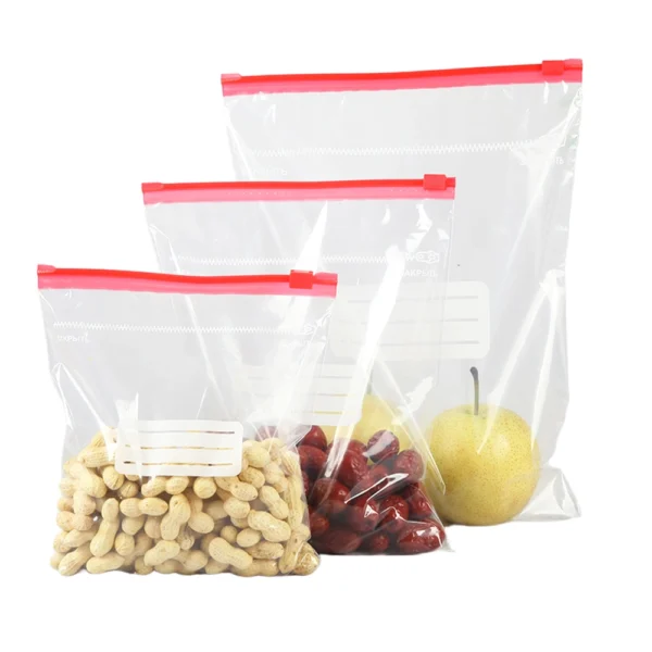 Clear food storage bags reusable with red slider closure holding peanuts, dried fruits, and fresh pear for organized kitchen storage
