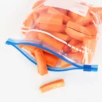 Clear reusable food storage bags holding sliced carrots with writable label area
