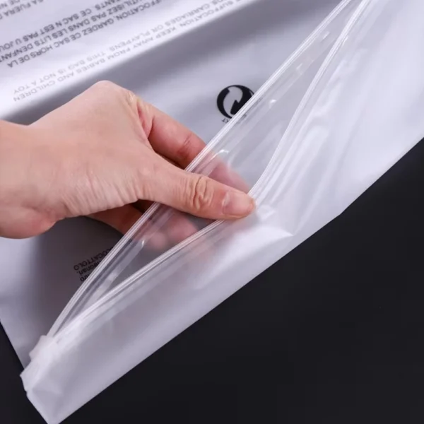 Hand opening a resealable biodegradable bag showing reinforced zip seal